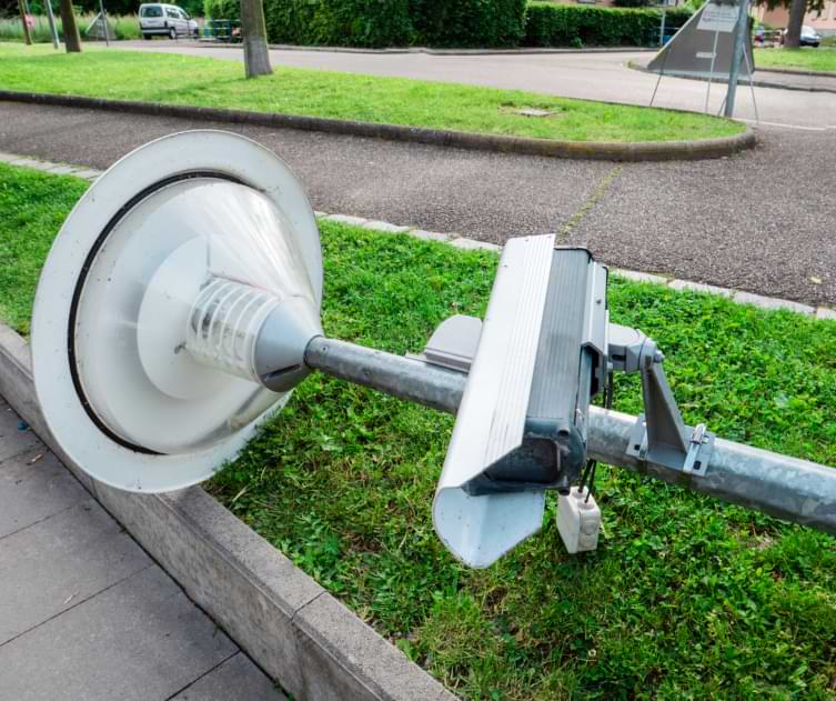 Broken street lamp with a surveillance camera for security negligently laying on the ground 